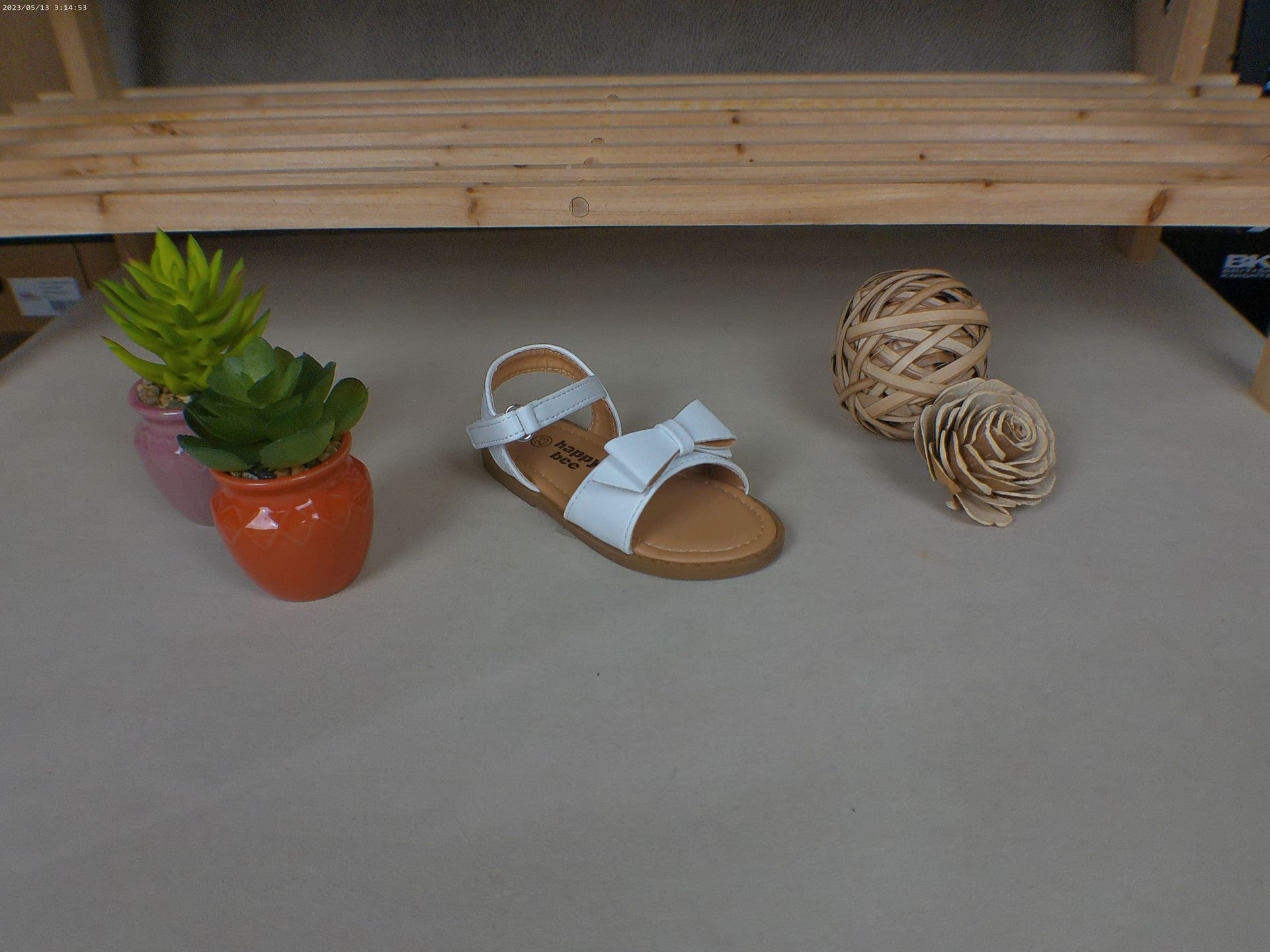 Een paar witte sandalen staan ​​op een tafel naast een potplant.