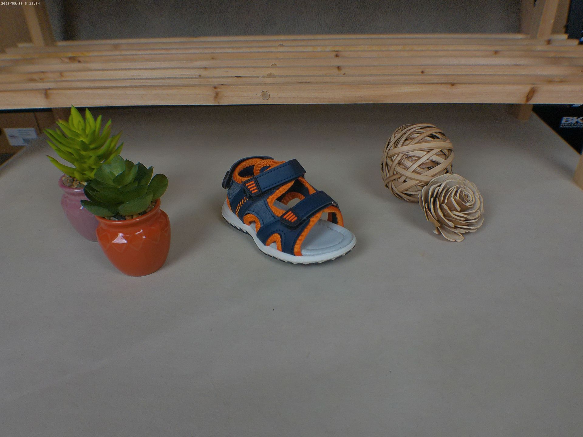 Een paar sandalen staat op een tafel naast een potplant.