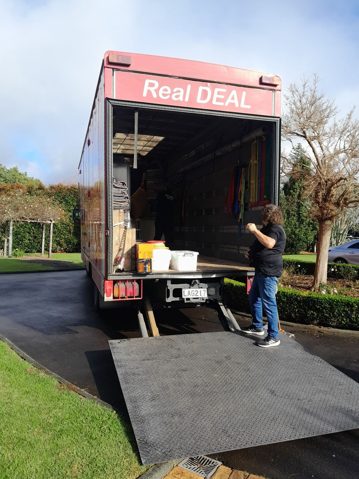 A man is standing on the ramp of a truck.