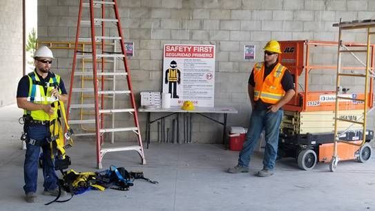 Two construction workers are standing in front of a safety first sign.