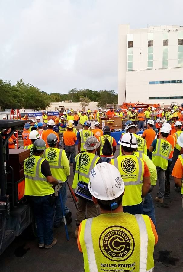 A group of construction workers wearing yellow vests and hard hats