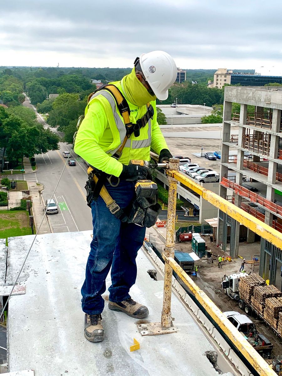 A construction worker is working on the side of a building.