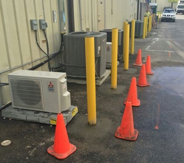 A mitsubishi air conditioner sits next to a row of orange cones