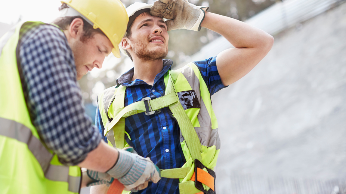 Two construction workers are standing next to each other on a construction site.