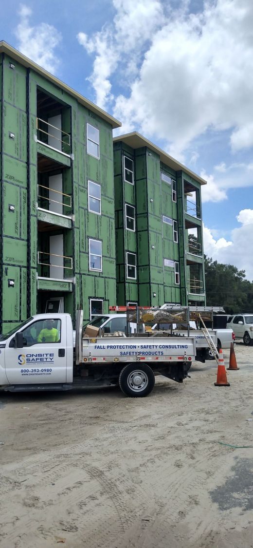 A white truck is parked in front of a building under construction.