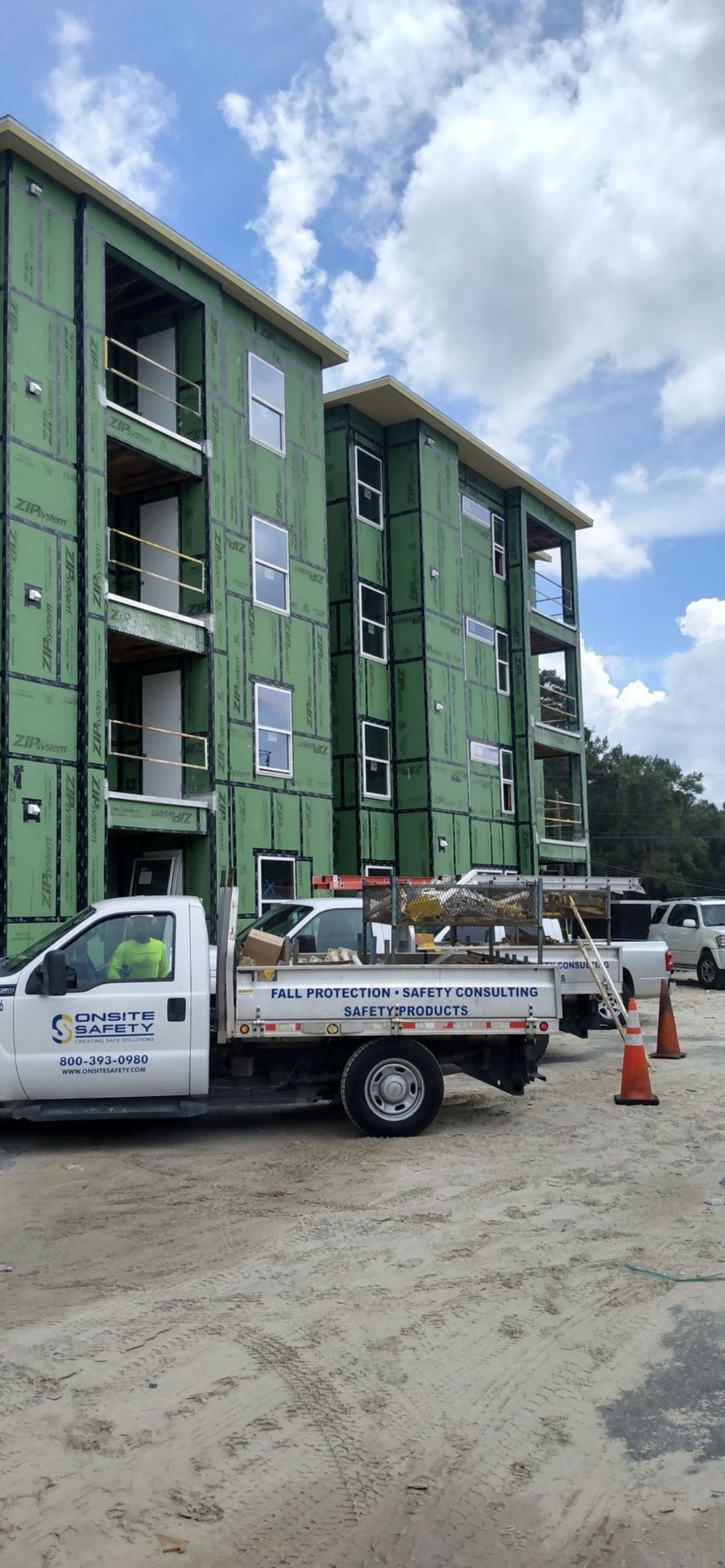 A white truck is parked in front of a building under construction.