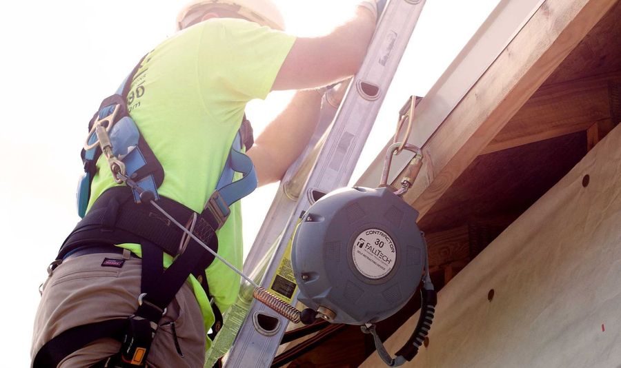 A man wearing a safety harness is climbing a ladder.