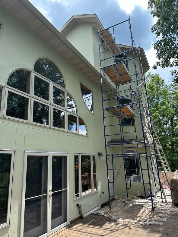 Two-story house with arched windows and scaffolding against the exterior wall during renovation