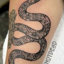 A black and white snake tattoo on a person 's arm.