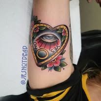 A person has a heart shaped ouija board tattoo on their arm.