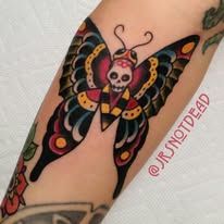 A tattoo of a butterfly with a skull on its head on a forearm.