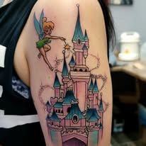 A woman has a tinkerbell tattoo of a castle on her arm.