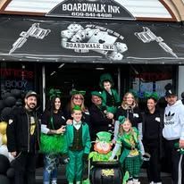 A group of people are posing for a picture in front of a tattoo shop.