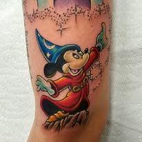 A tattoo of mickey mouse wearing a wizard hat on a leg.