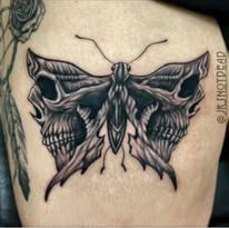 A black and white tattoo of a butterfly with skulls on its wings on a person 's back.