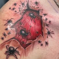 A close up of a tattoo of spiders on a person 's shoulder.