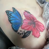 A blue butterfly and a red flower tattoo on a woman 's side.