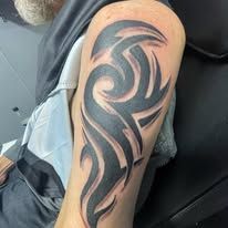 A man has a tribal tattoo on his arm.