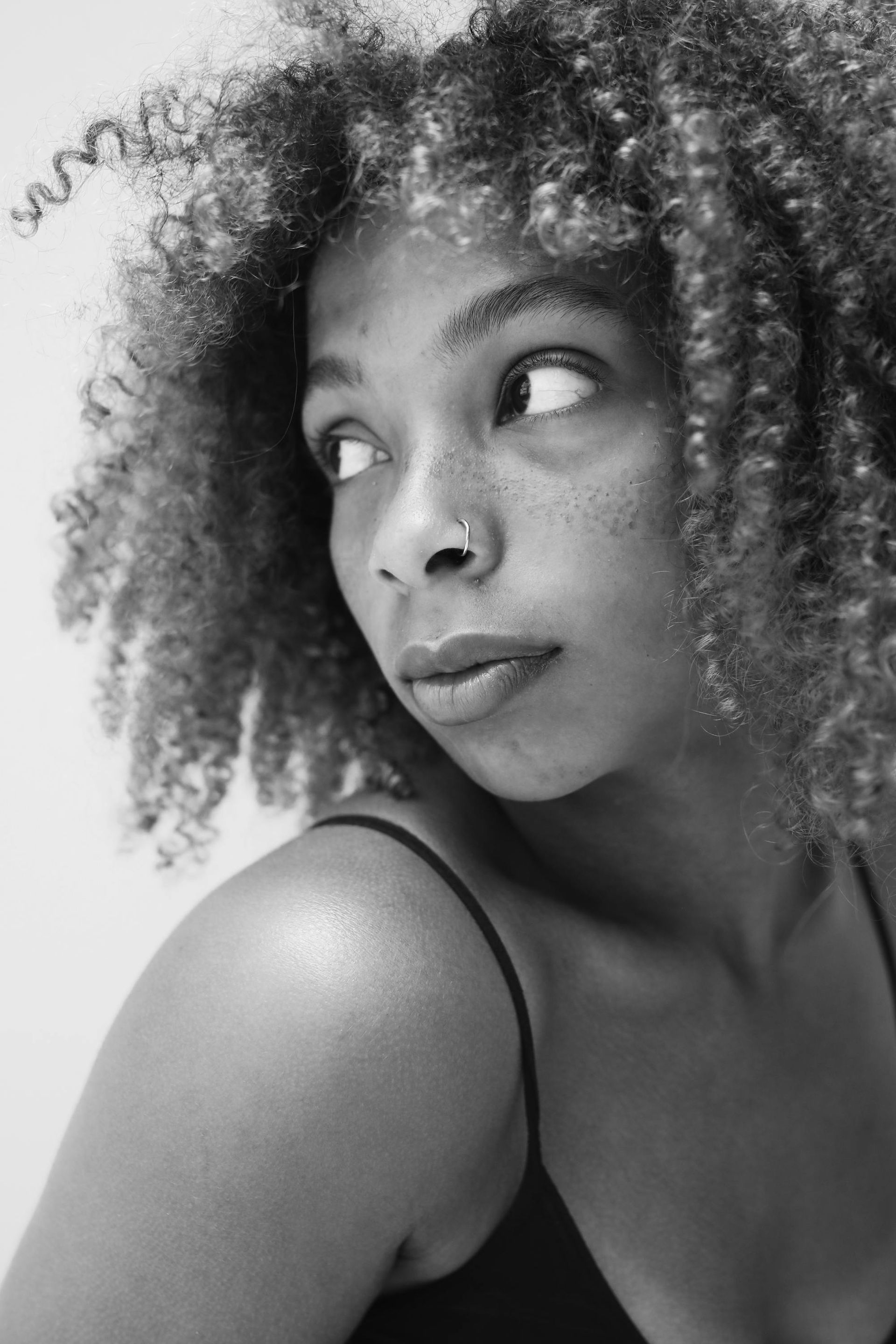 A black and white photo of a woman with curly hair and freckles.