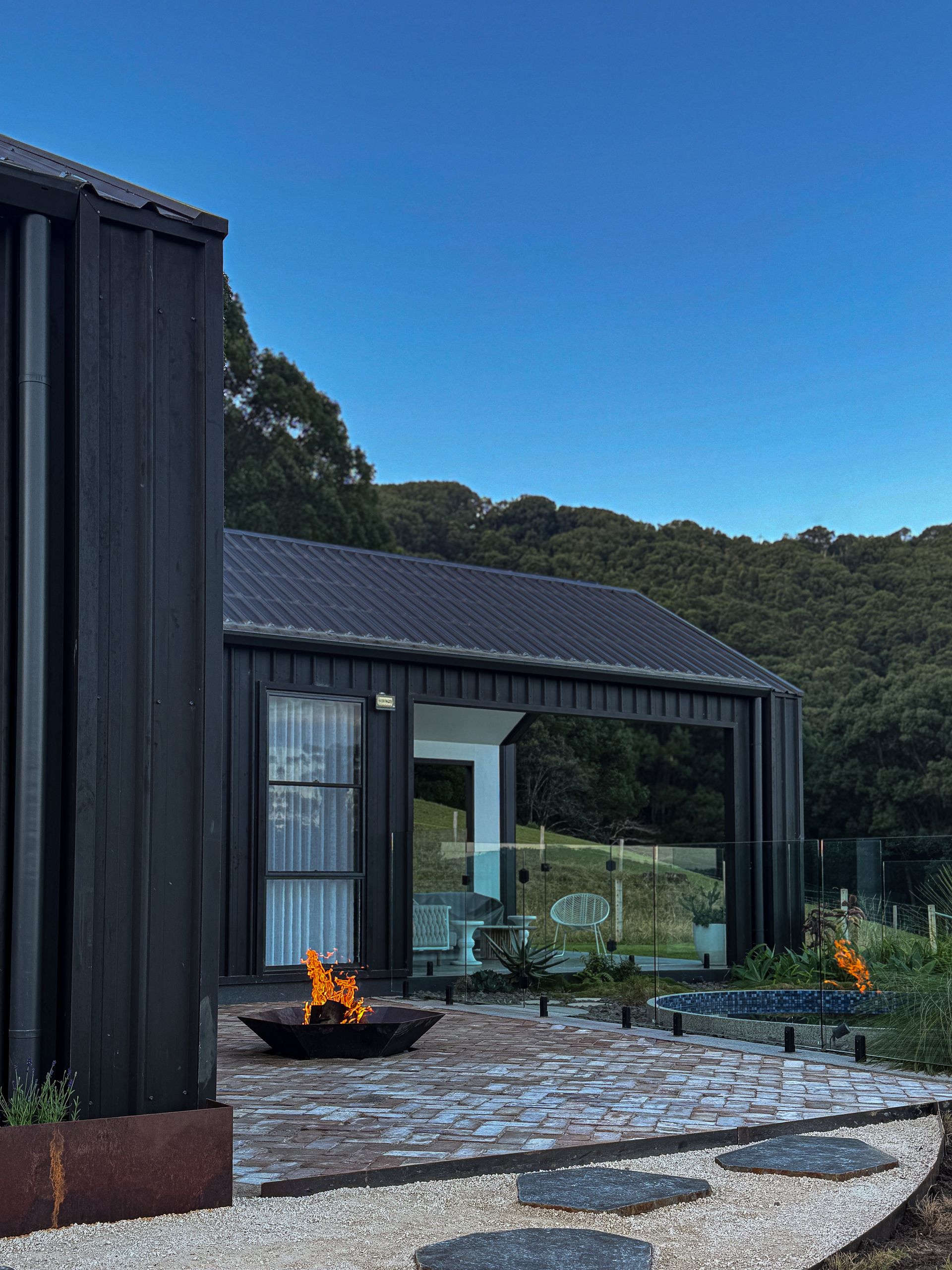A fire pit is surrounded by rocks and a white fence.