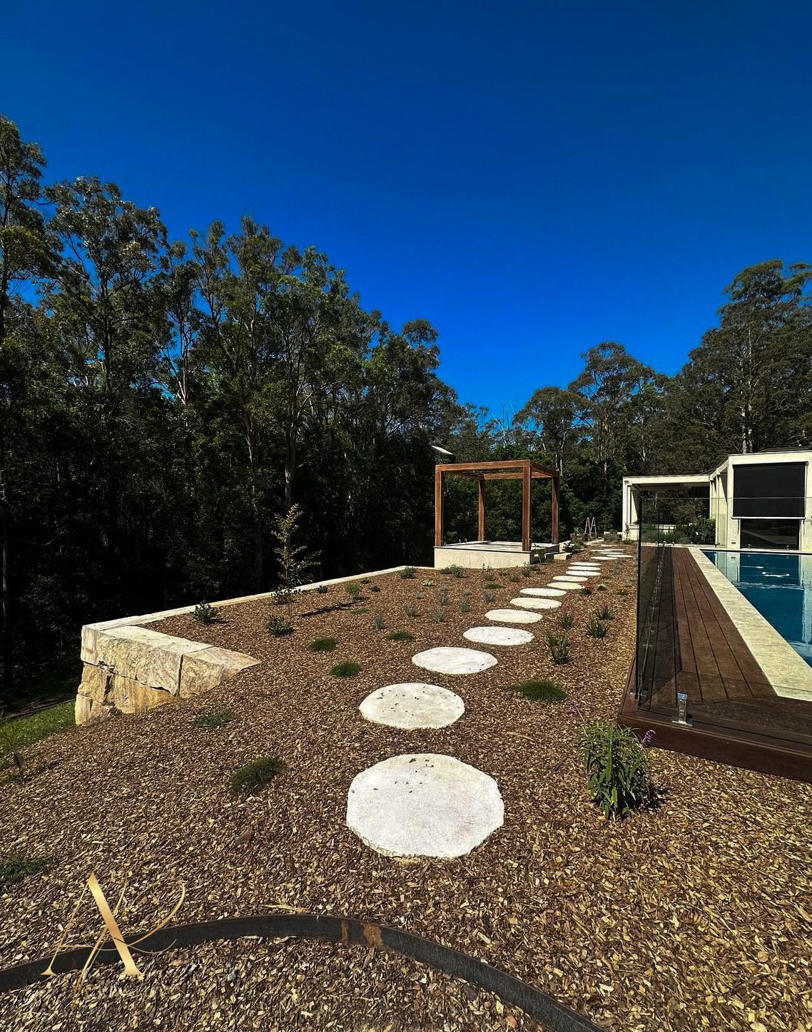 There is a swimming pool in the backyard with a path leading to it.
