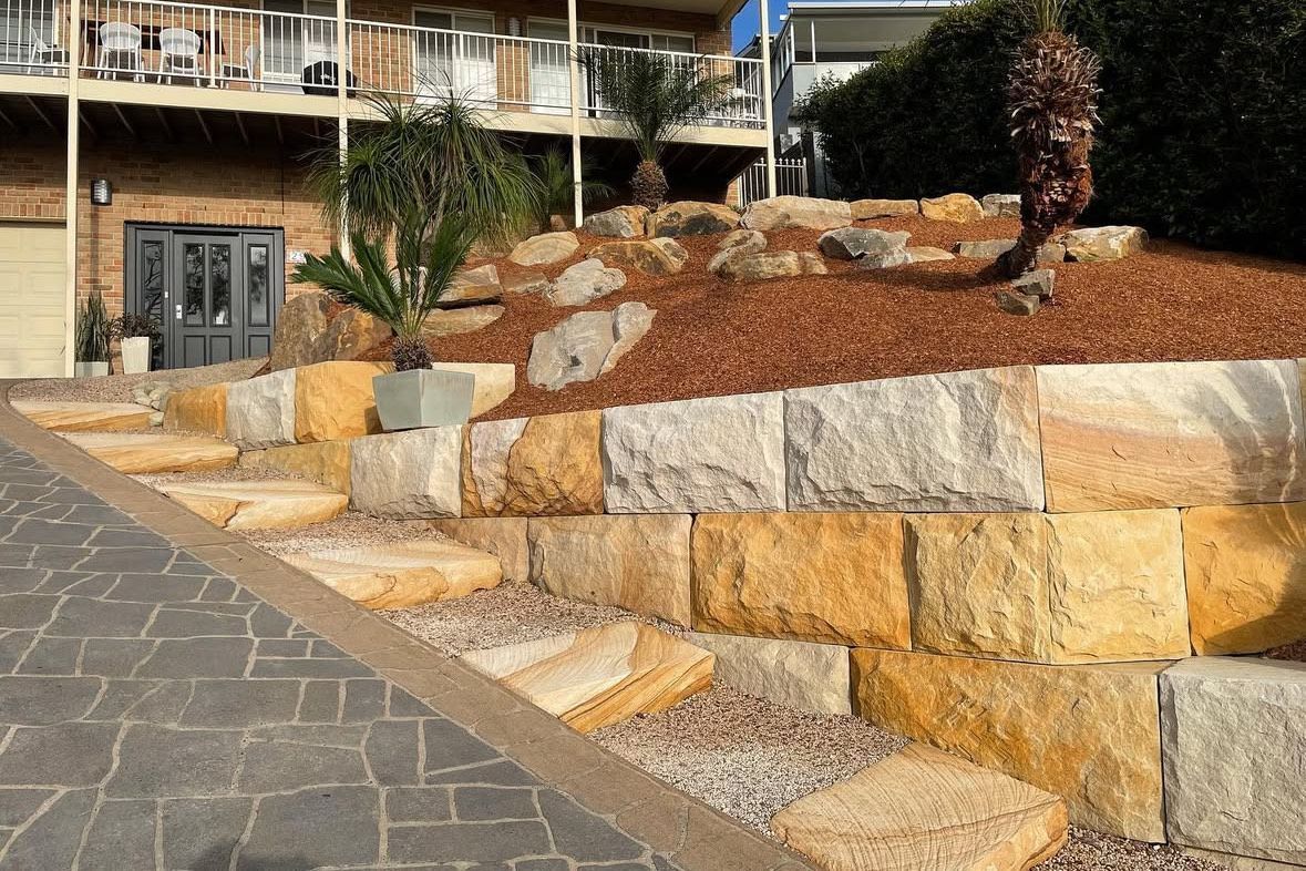 A stone wall with steps leading up to a house.