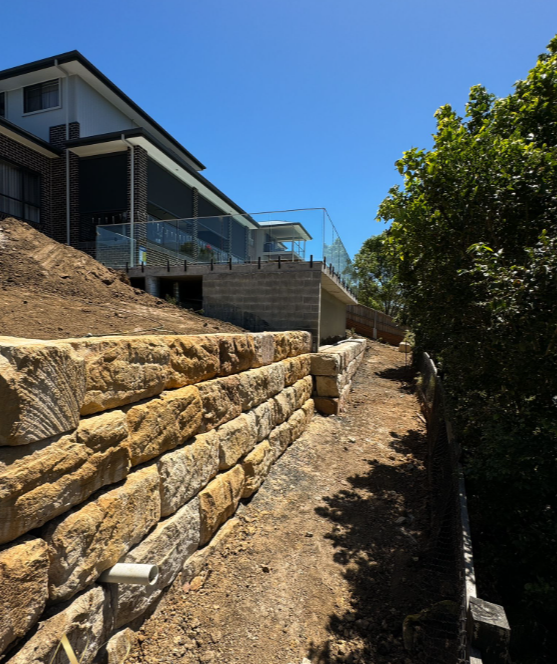 A house with a large stone wall in front of it