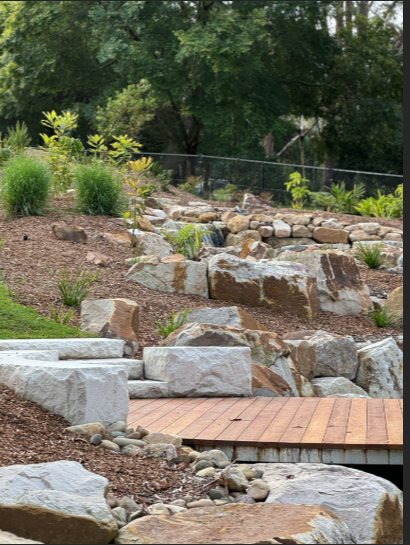 There is a wooden bridge in the middle of a rocky area.