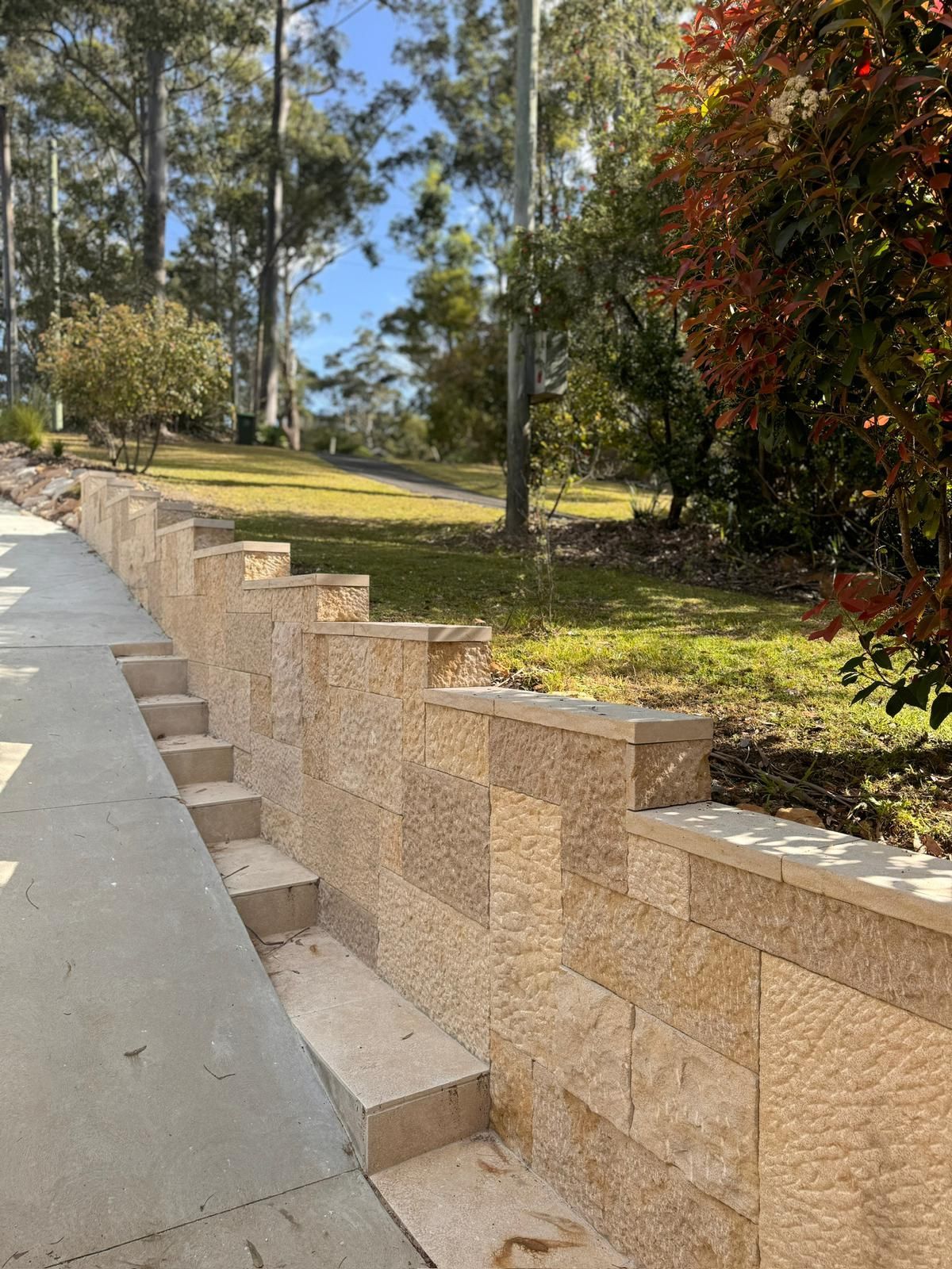A stone wall with stairs leading up to it in a park.