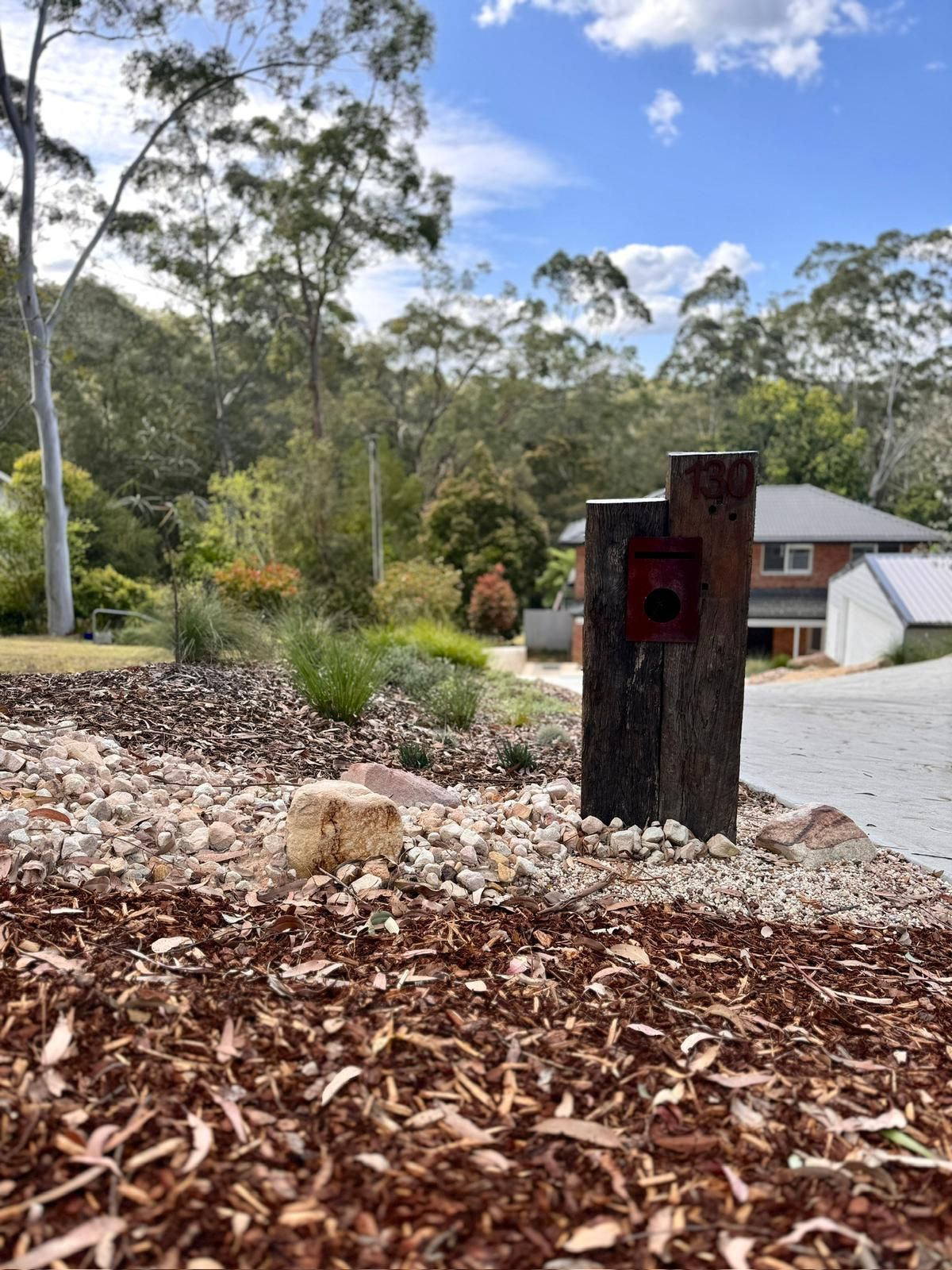 A mailbox is sitting in the dirt in front of a house