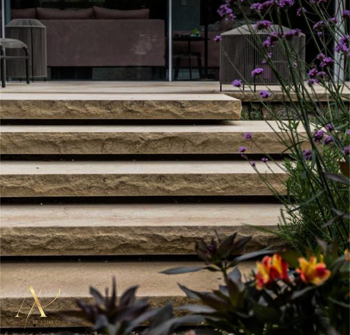A set of stairs leading up to a house with flowers in the foreground.