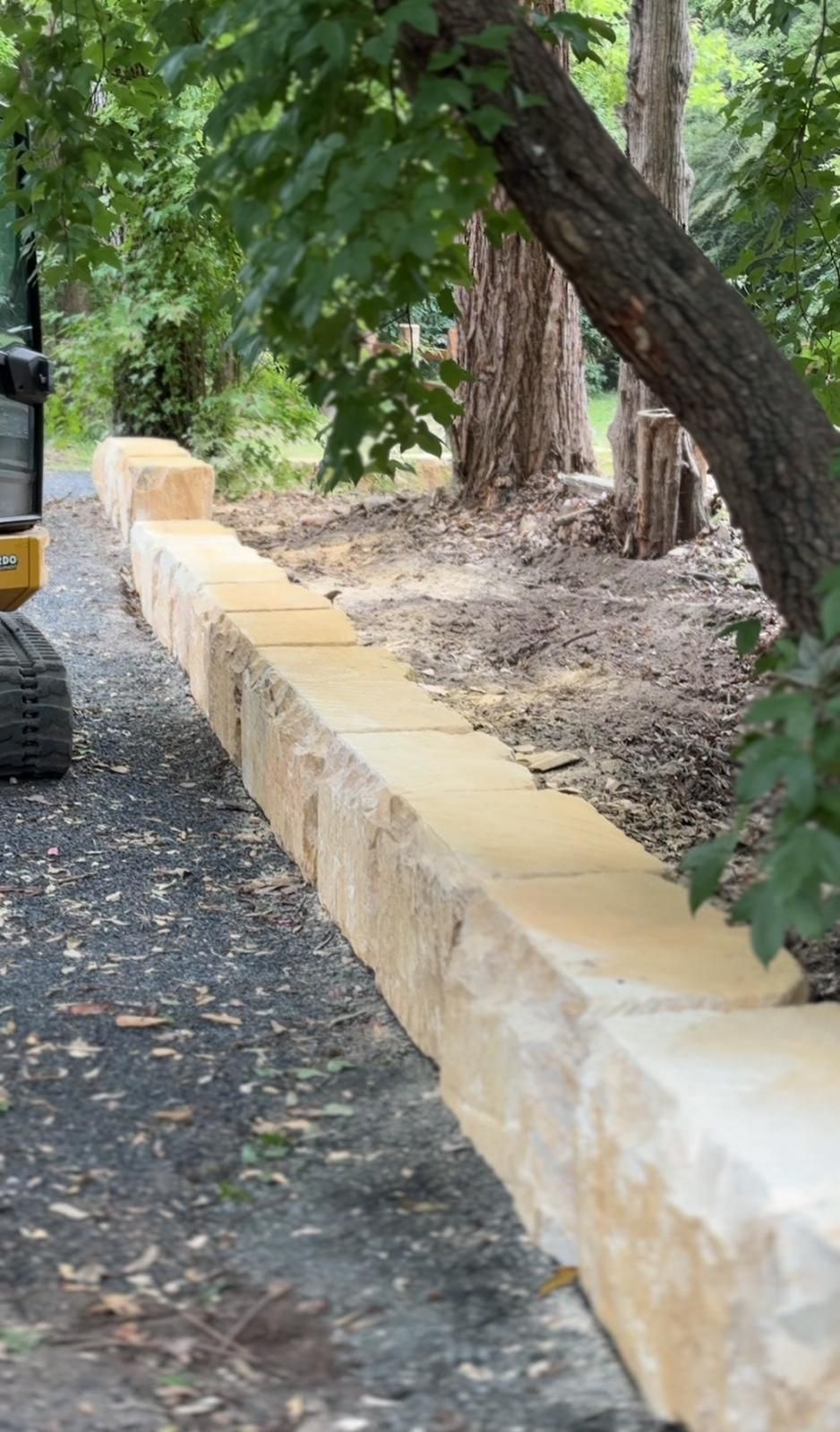 A large stone wall is being built next to a tree.