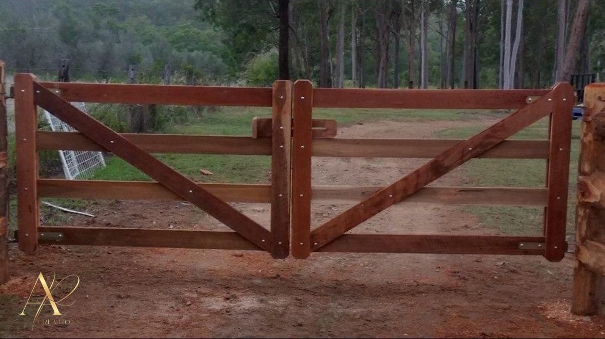 A wooden gate is sitting in the middle of a dirt field.