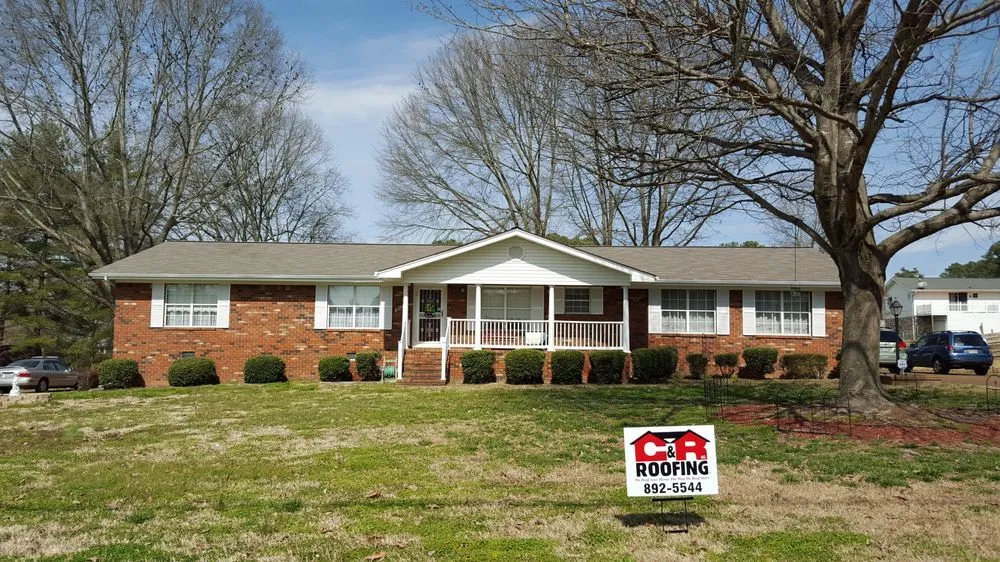 Brick ranch-style house with a porch and a real estate sign in the front yard.