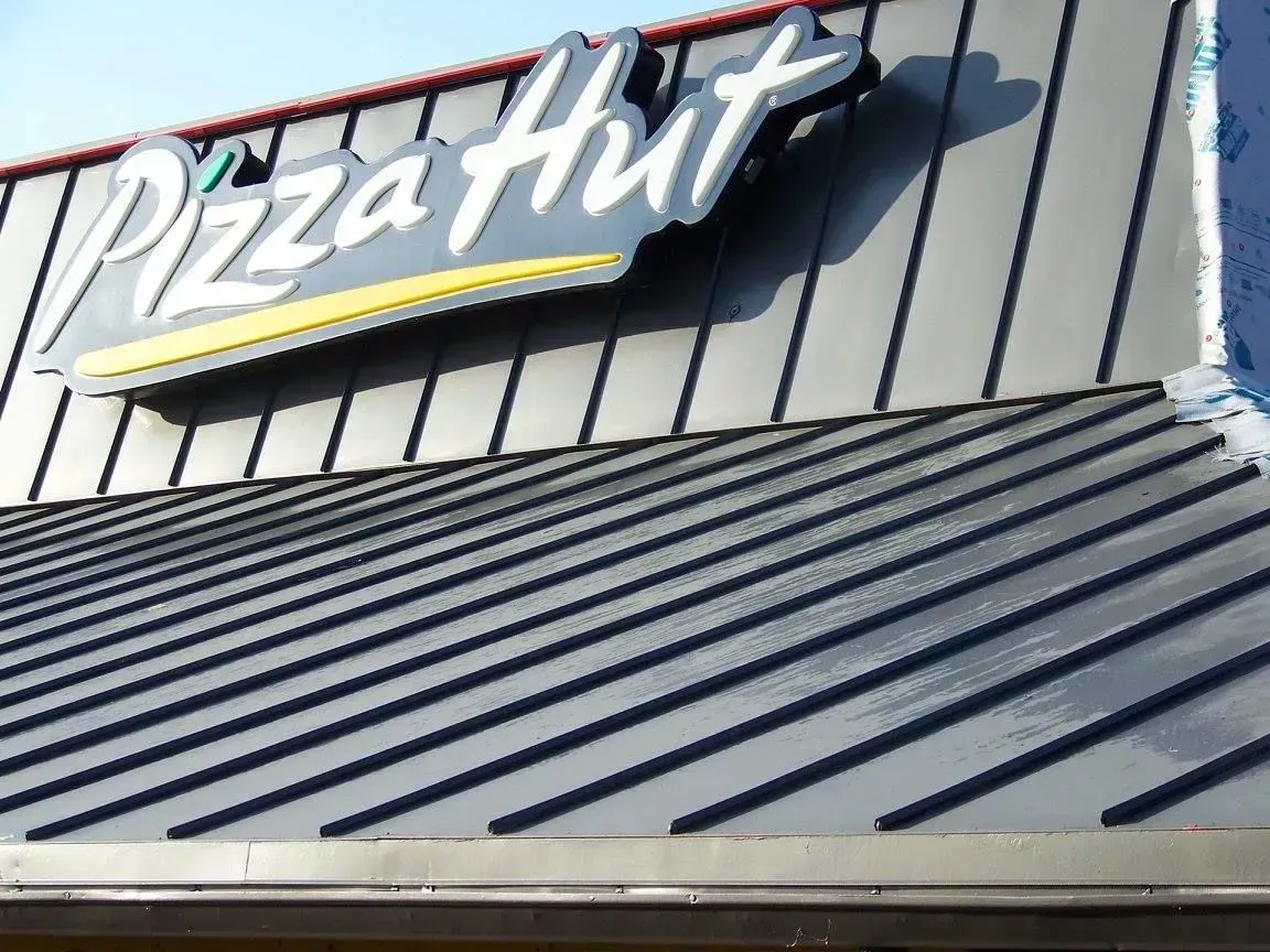 Pizza Hut sign above a dark gray, ribbed metal roof.