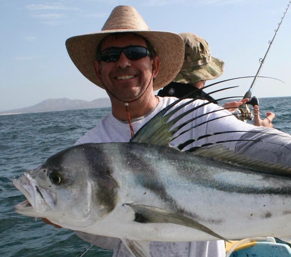 Group of people waving from a pontoon boat on a sunny day at sea.
