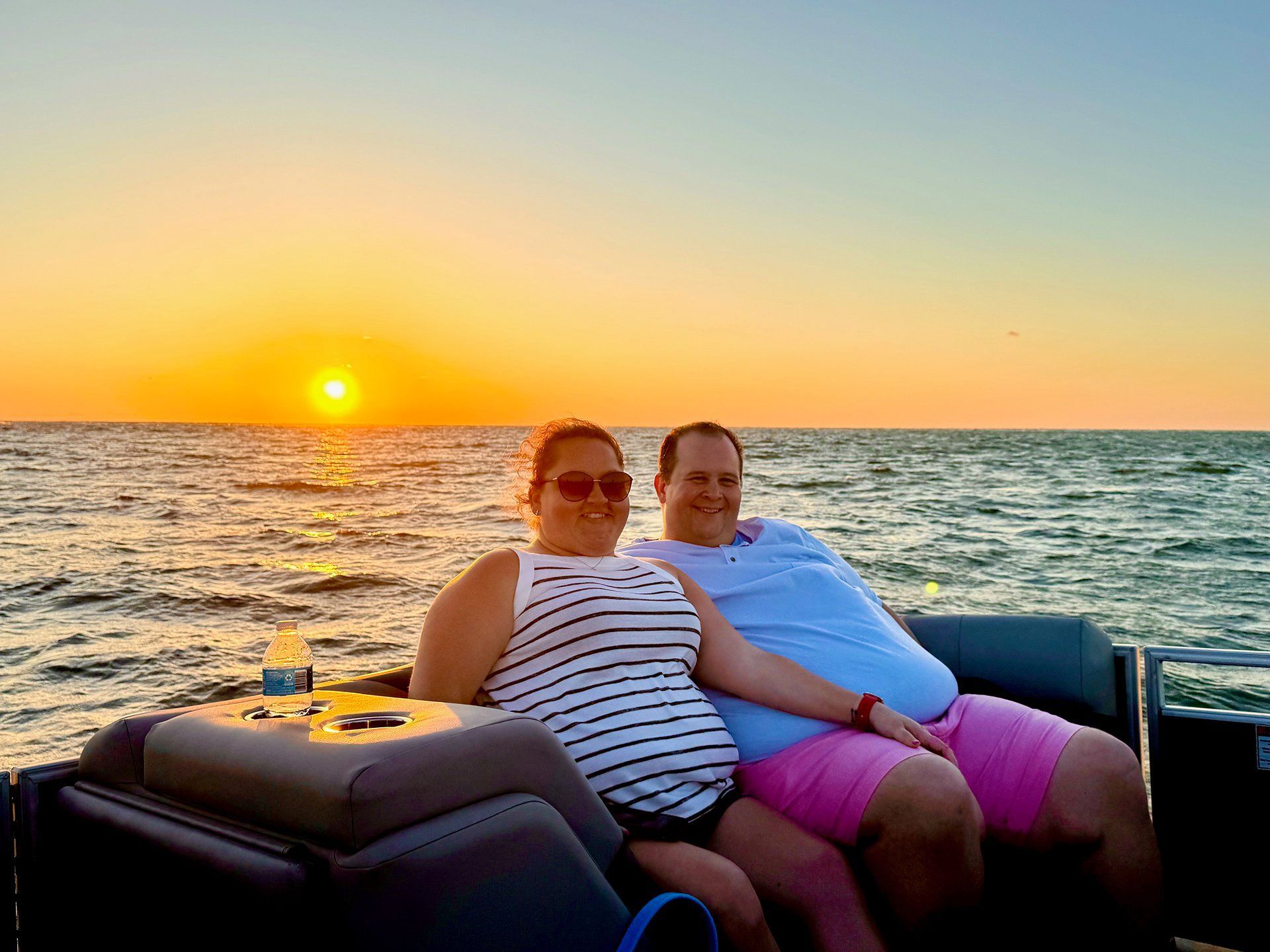 Couple on a boat watching a sunset over the water.
