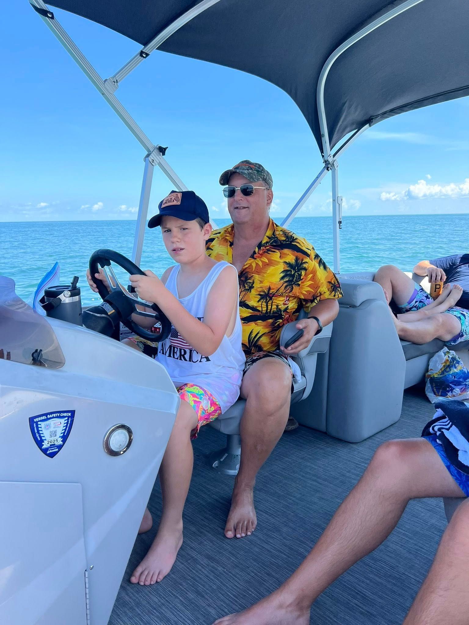 Grandfather and grandson driving pontoon boat.