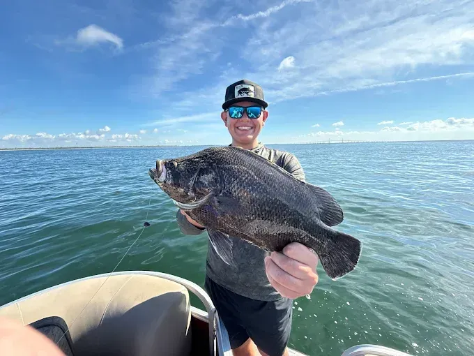 Group of people waving from a pontoon boat on a sunny day at sea.
