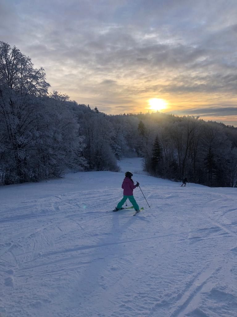 Skiing down a snow slope during sunset.