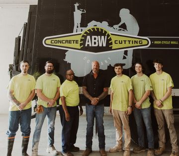 A group of men standing in front of a concrete cutting truck