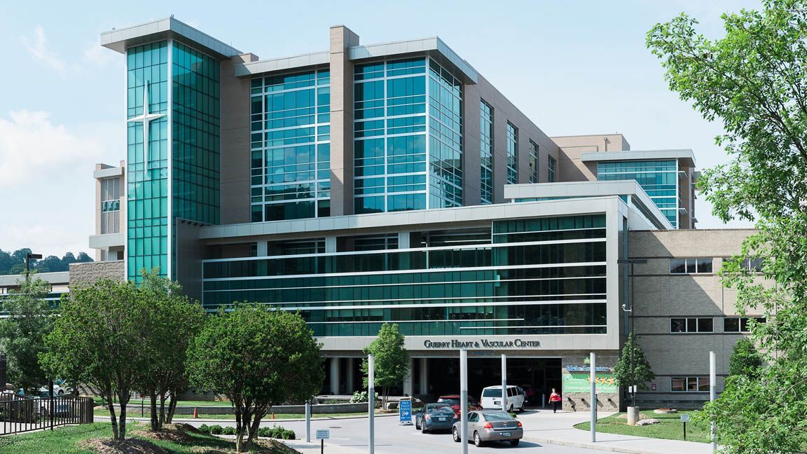 A large building with a lot of windows and cars parked in front of it.