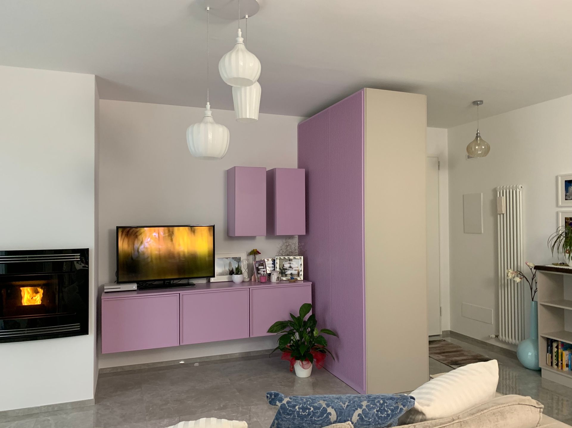 Un soggiorno con mobili viola, una TV a schermo piatto e un camino.