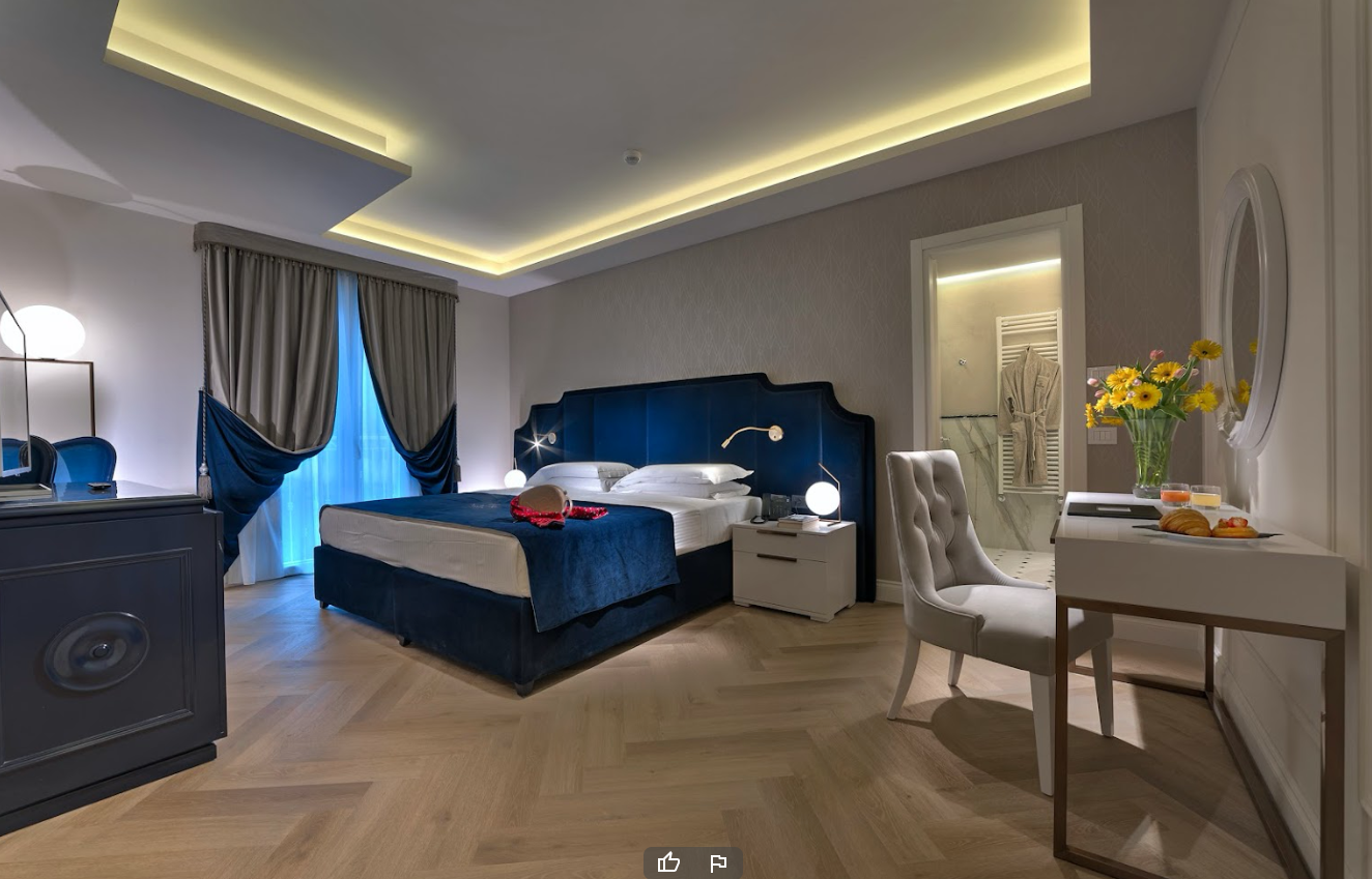 Una camera d'albergo con un letto grande, una cassettiera, una sedia e una scrivania.