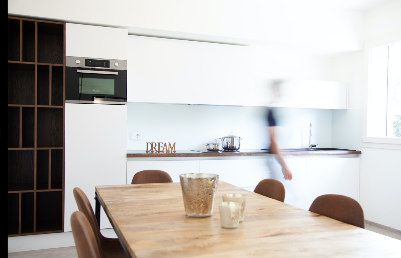 Una cucina con un tavolo e delle sedie e un uomo sullo sfondo