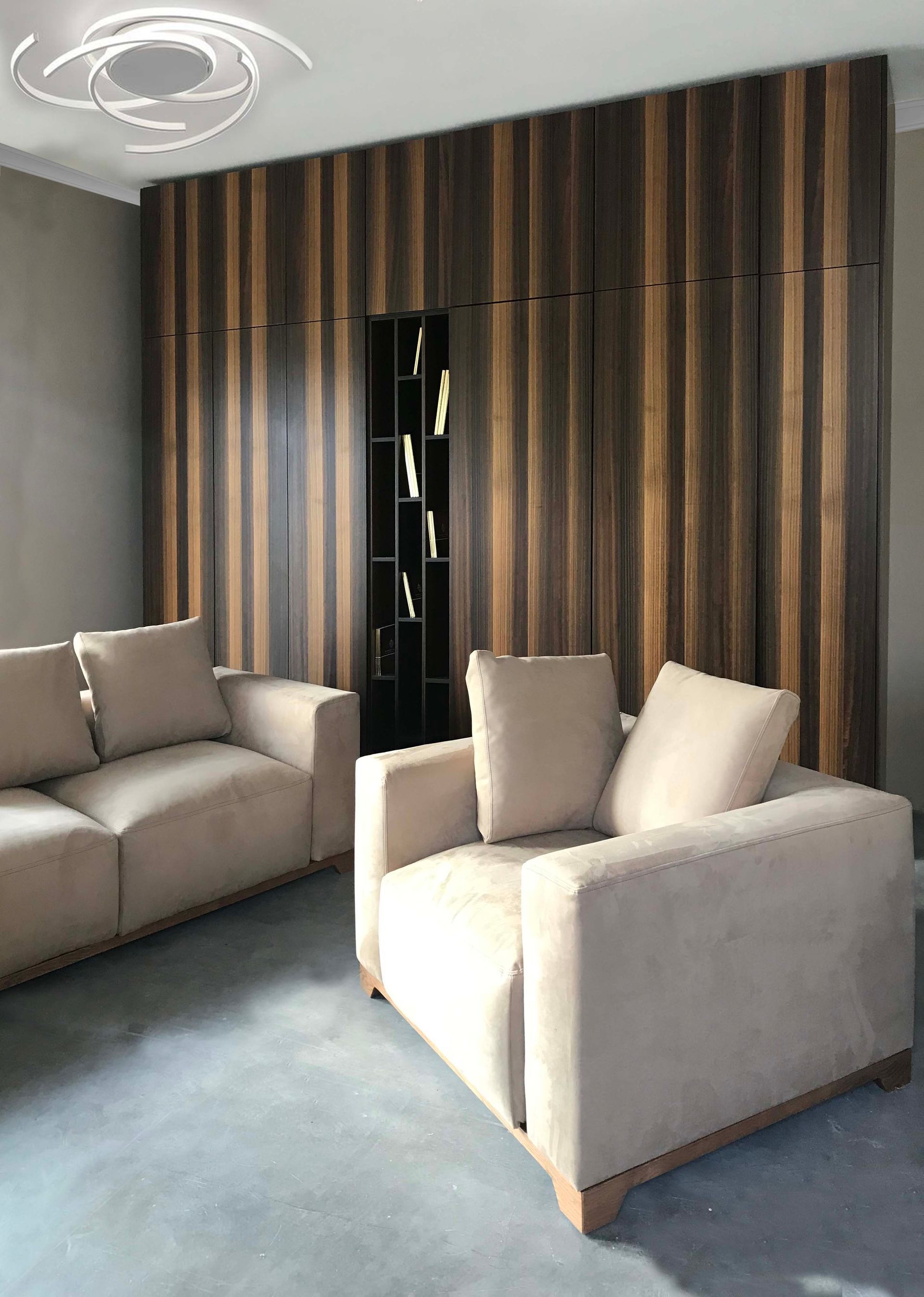 Un soggiorno con un divano e una sedia di fronte a una parete di legno.