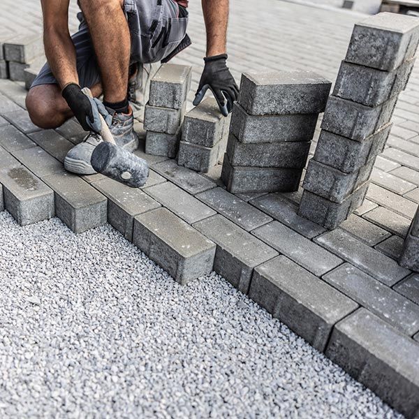 Worker Laying Concrete Grey Paving Tiles — Haverstraw, NY — K & P Asphalt Inc