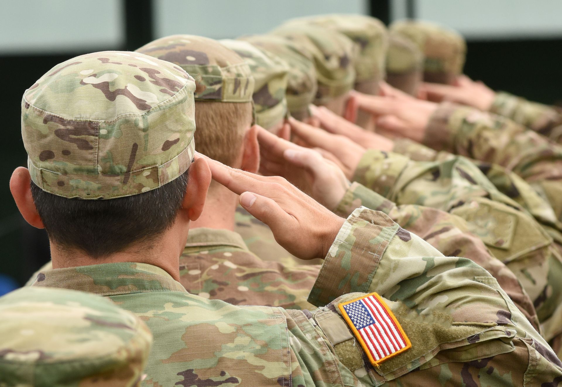 A group of soldiers are saluting in a row.