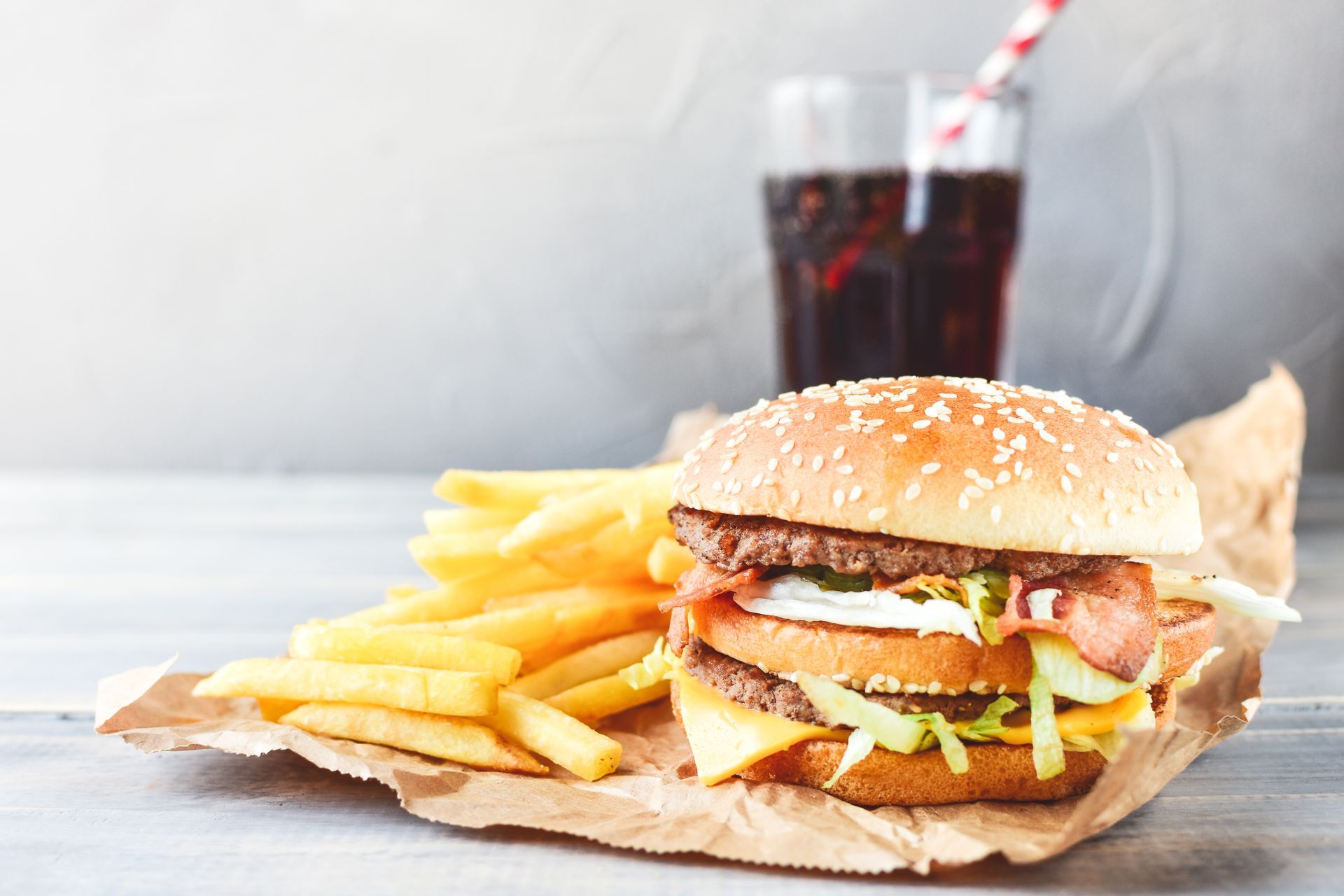 A hamburger , french fries and a glass of soda on a table.