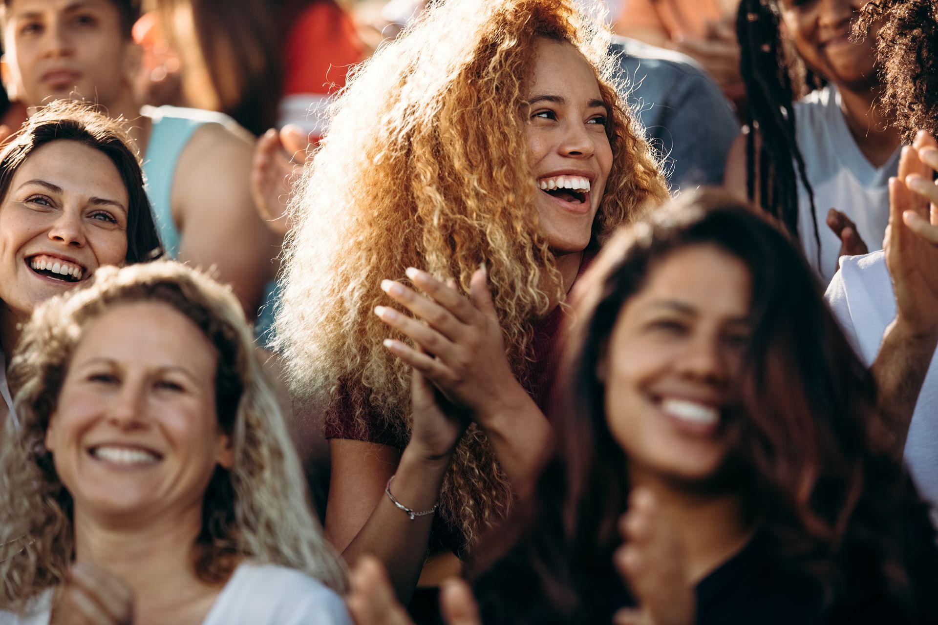 A group of people are laughing and clapping in a crowd.